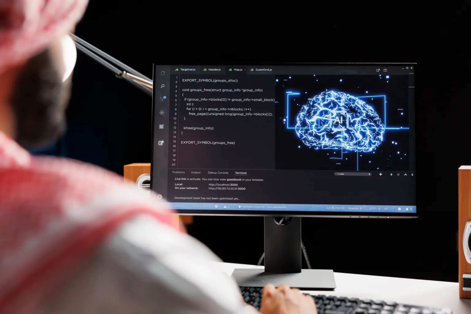 A person working on a computer with the screen showing coding, neural networks, and a computer generated brain